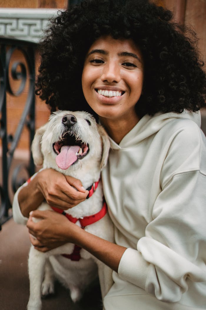 Smiling woman embraces her joyful dog outside, capturing a moment of friendship and happiness.